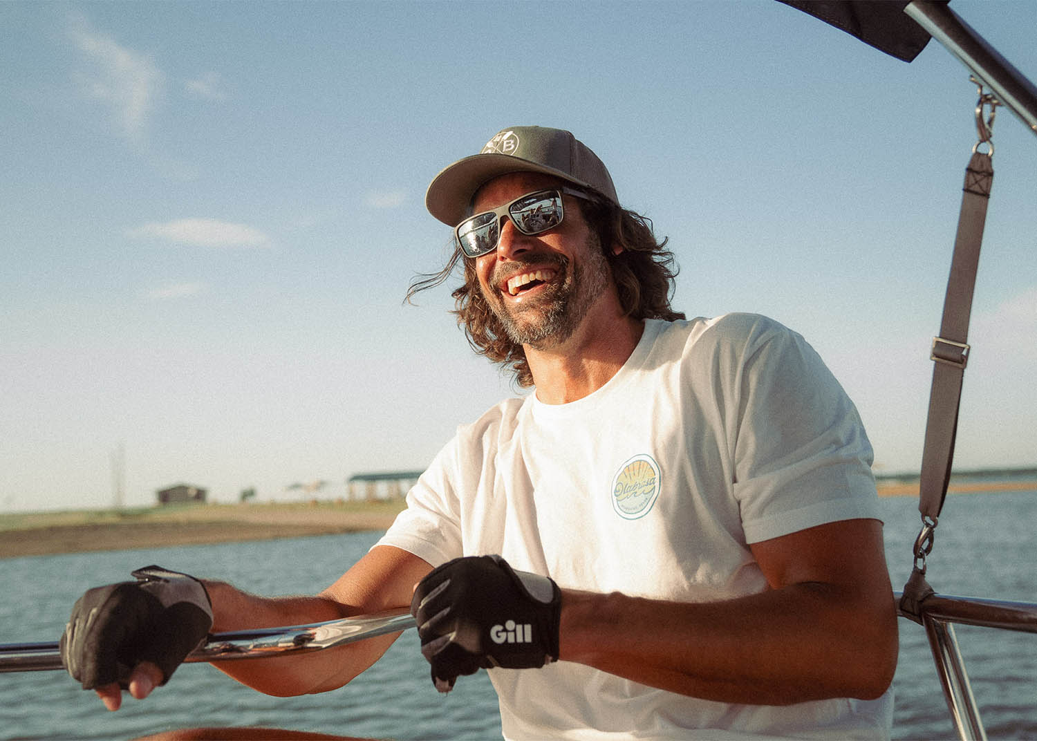 Man steering a boat on water wearing Olabrasa merch.