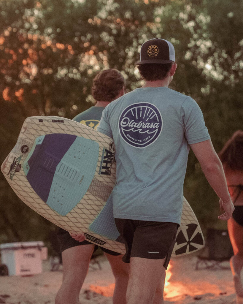Surfers walking to campfire wearing Olabrasa OG T-Shirt and Paddle SnapBack Curved Hat