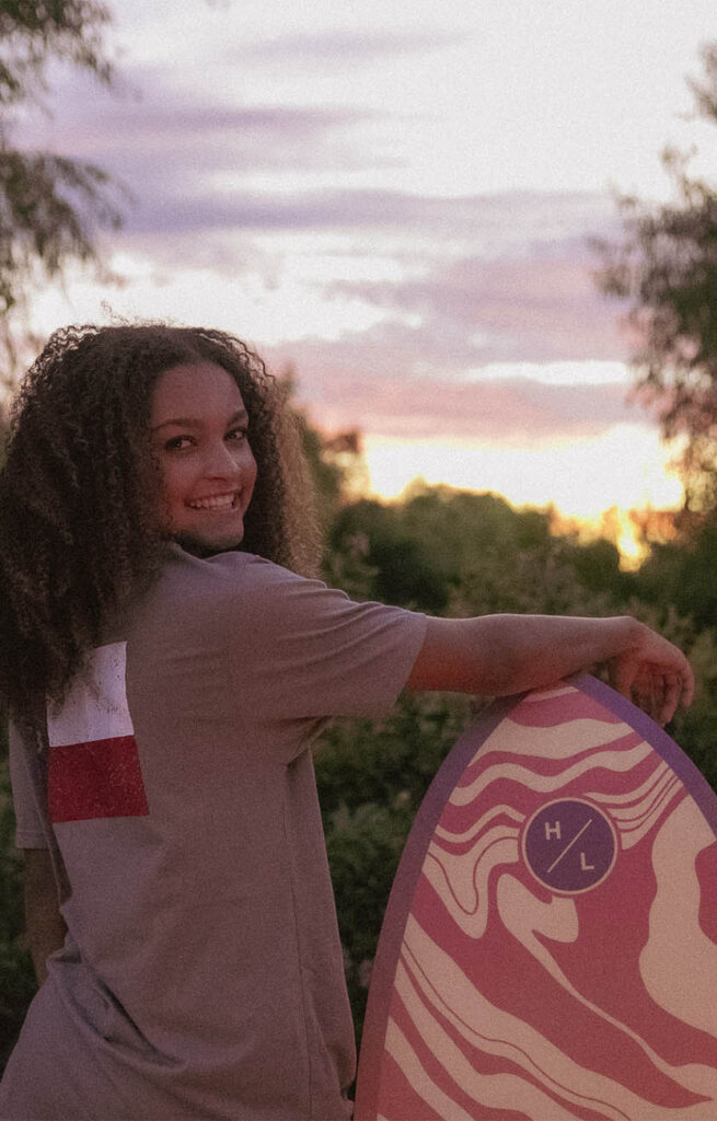 Person with surfboard at sunset wearing Texas Forever T-Shirt.