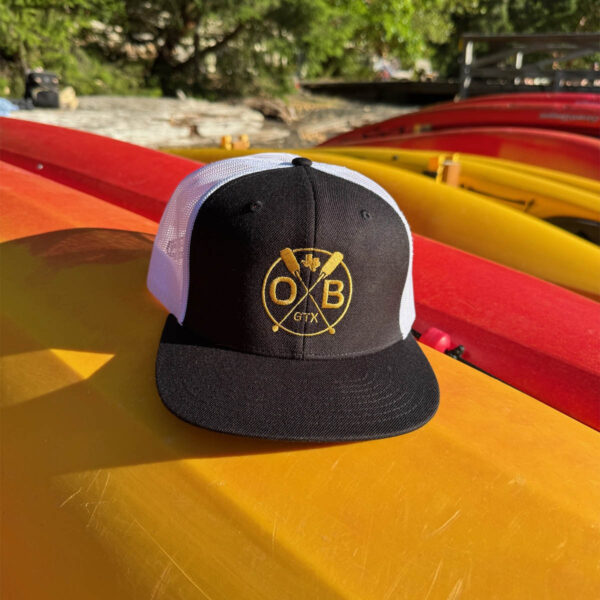 Olabrasa Paddle Curved SnapBack Hat laying on canoe