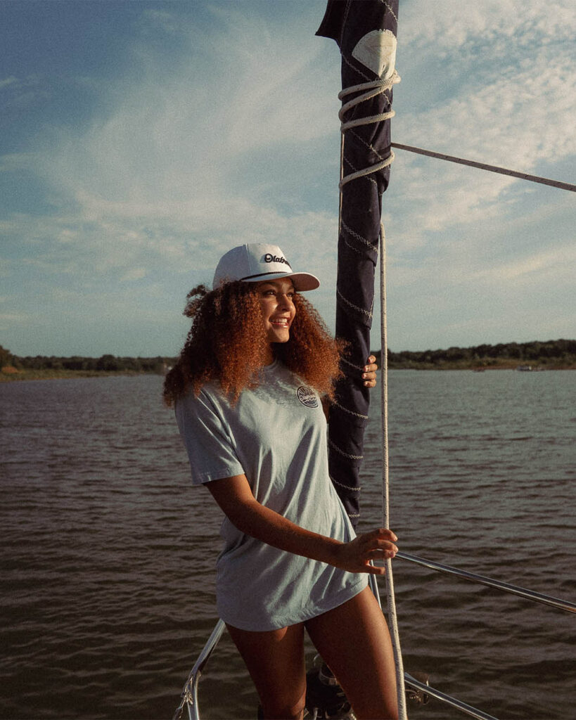 Young woman smiling on boat wearing Olabrasa merch