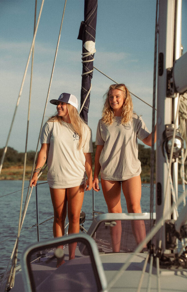 Two women on a sailboat wearing Olabrasa merch.