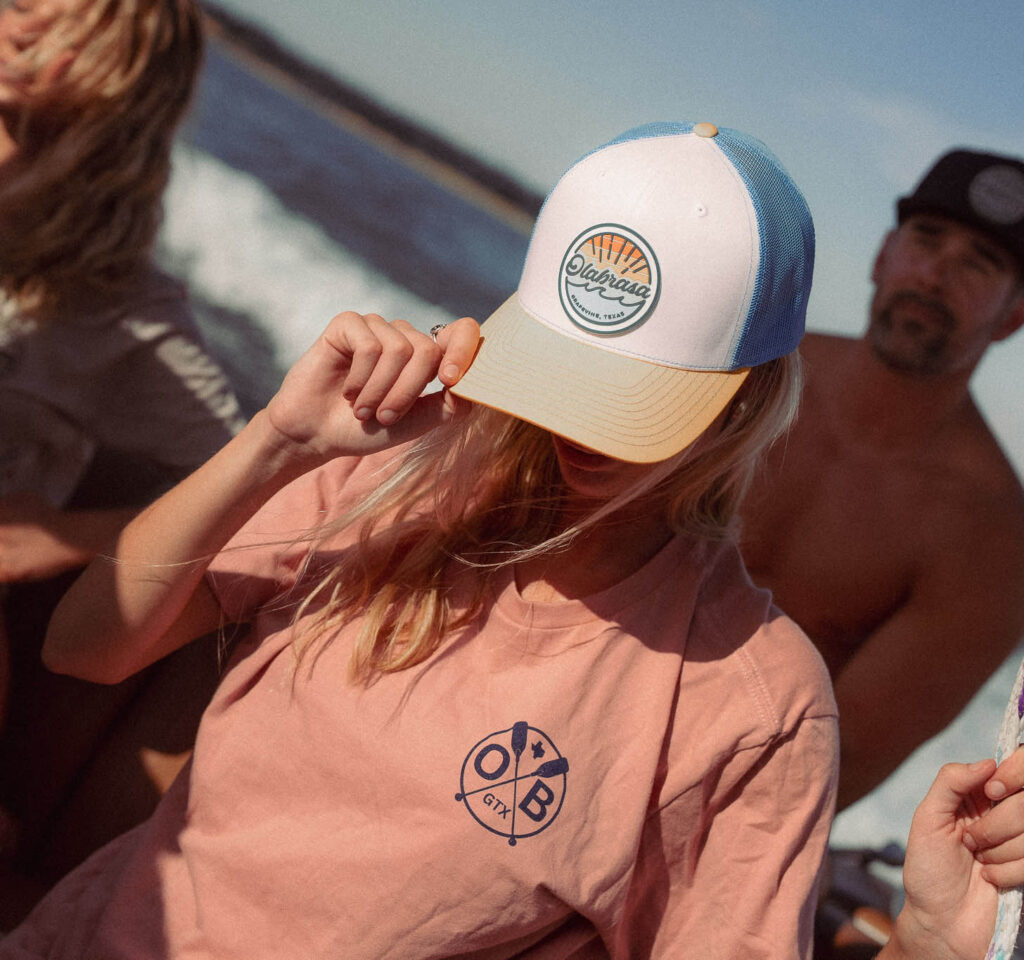 Young woman wearing the Olabrasa OG Curved SnapBack Hat and Dusty Rose Paddle T-Shirt.
