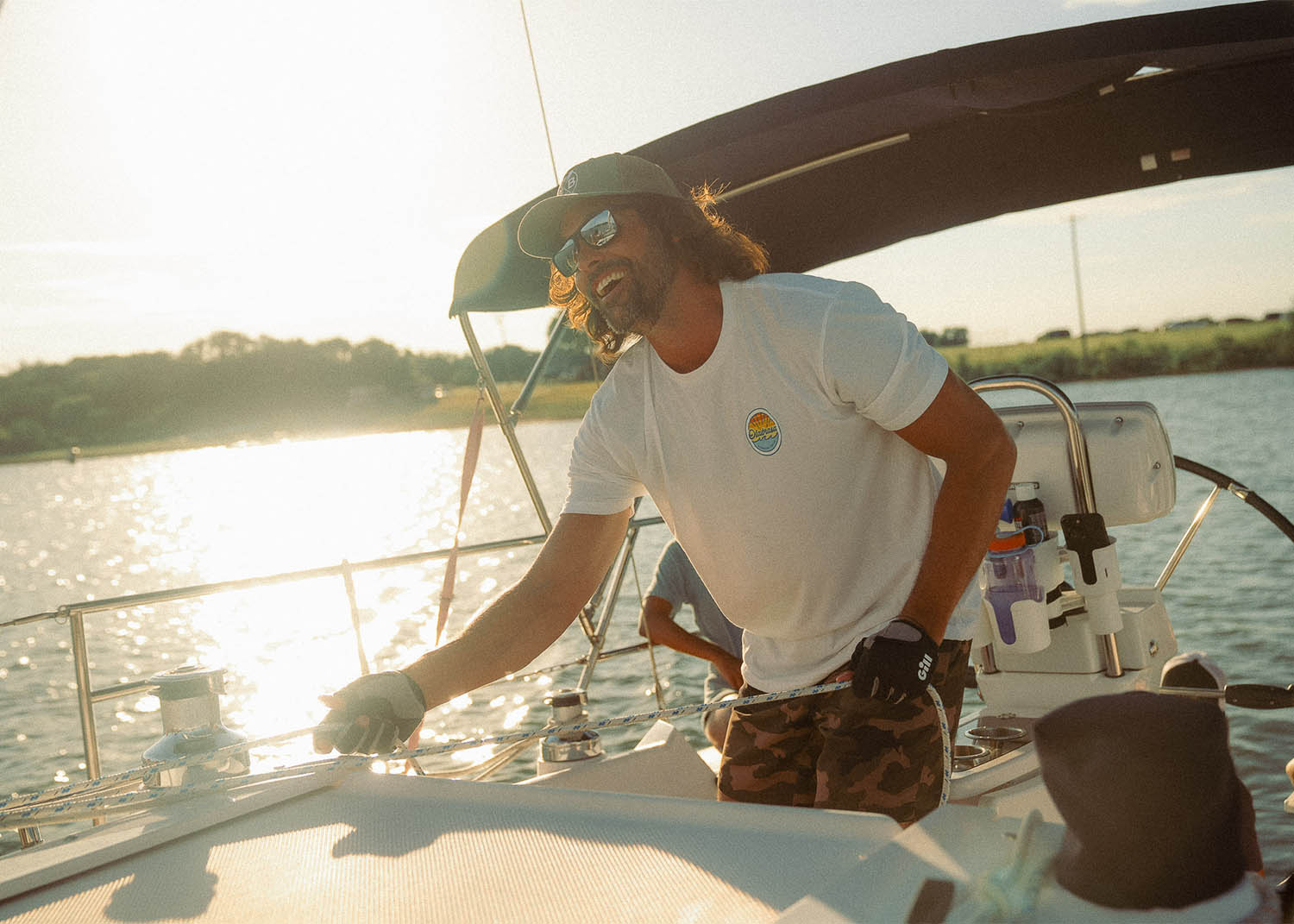 Man sailing on a sunny day while wearing Olabrasa OG T-Shirt and Paddle Curved Hat.