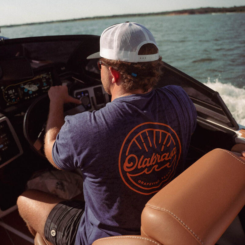 Man driving a boat wearing Olabrasa OG T-Shirt
