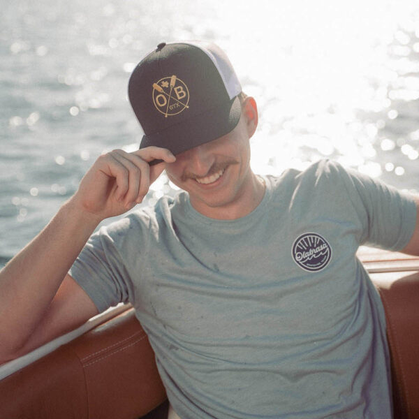 Man enjoying a sunny boat ride wearing Olabrasa OG T-Shirt and Olabrasa Paddle Flat SnapBack hat